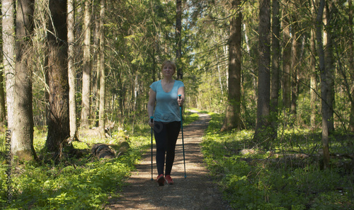 Mature woman with trekking poles walking in the forest