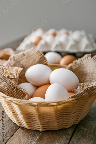 Fresh chicken eggs in basket on wooden table