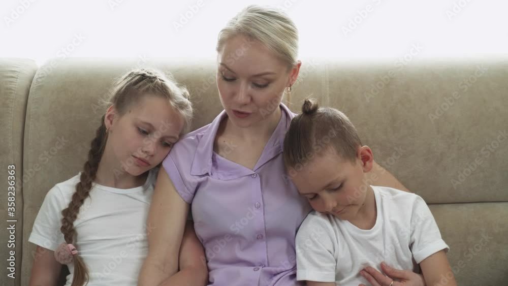 Motherhood, mother reads a fairy tale to her children, read a book, daughter and son sit next to mother on the sofa and listen. Motherhood, mother reads a fairy tale to her children, read a book, daughter and son sit next to mother on the sofa and listen.