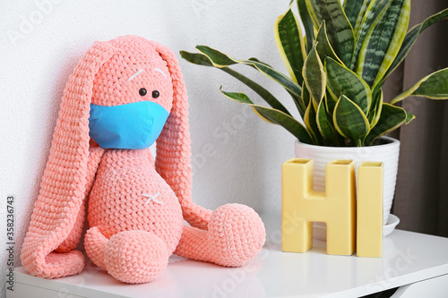 Childhood health and safety, handmade pink crochet bunny toy wearing a blue p...