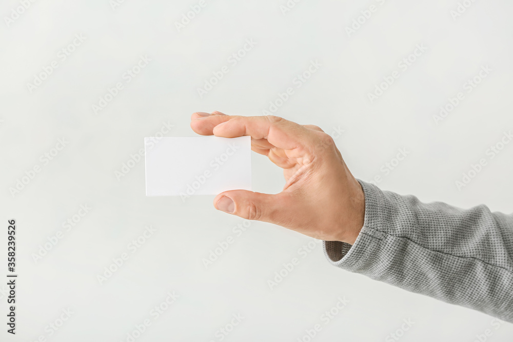 Male hand with blank business card on light background Male hand with blank business card on light background