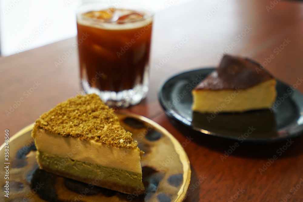 Close up Basque burnt and Matcha green tea cheesecake served with iced black coffee Close up Basque burnt and Matcha green tea cheesecake served with iced black coffee