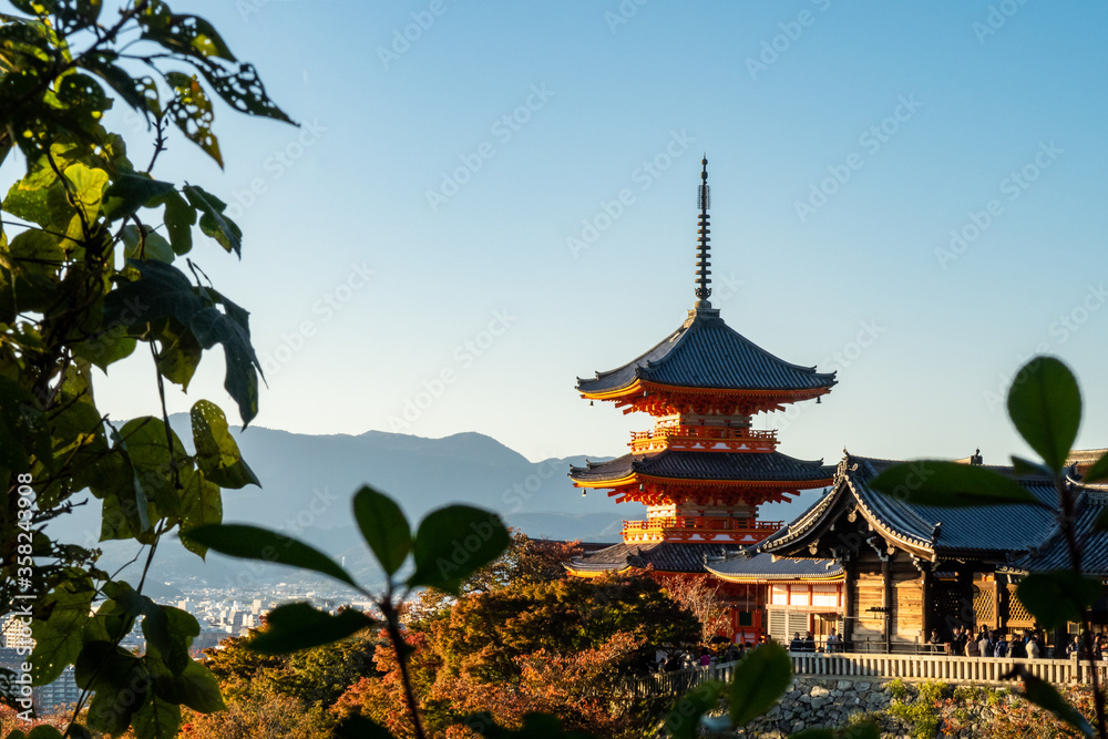 Buddhist Temple and Pagoda Kiyomizu-dera in Kyoto - autumn view through the leaves with clear blue sky, Japan. Buddhist Temple and Pagoda Kiyomizu-dera in Kyoto - autumn view through the leaves with clear blue sky, Japan.