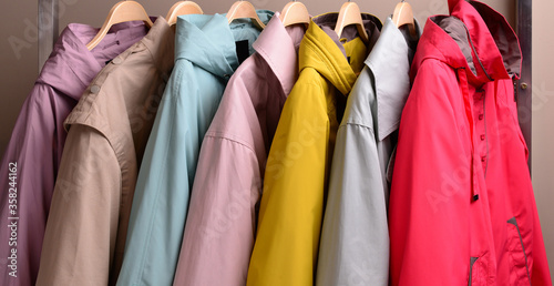 New collection of different color spring raincoats for women. Colorful background of modern spring, autumn outerwear.