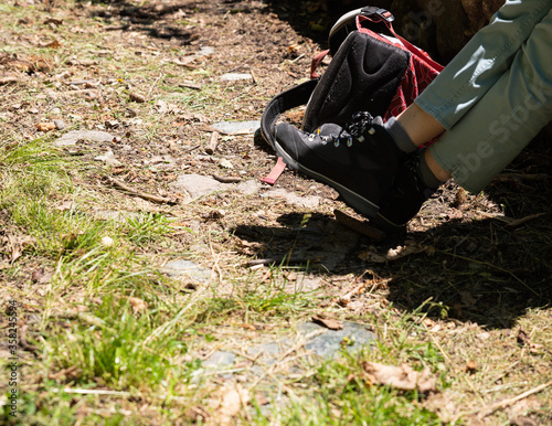 Close-up on a woman's boots: a moment of pause during the walk. The backpack is lying next to it. Nice sunny day. photo