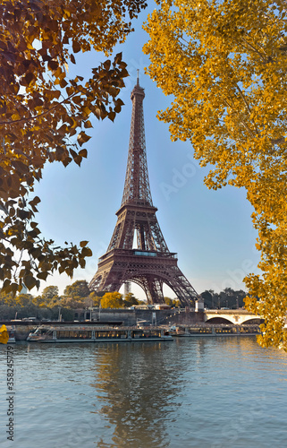 eiffel tower in paris between yellow foliage in autumn view from seine river © coco