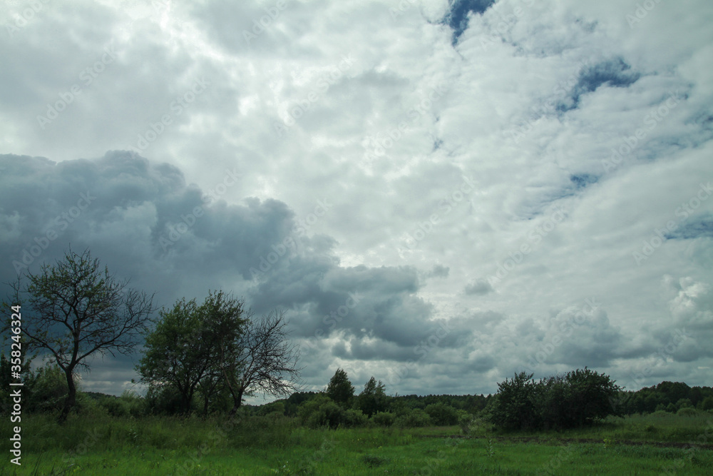 Thunderous epic clouds in a field near the old garden. Stock photo background with heaven. Thunderous epic clouds in a field near the old garden. Stock photo background with heaven.
