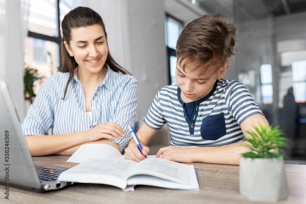 Obraz premium education, family and homework concept - smiling mother and son with book writing to notebook at home