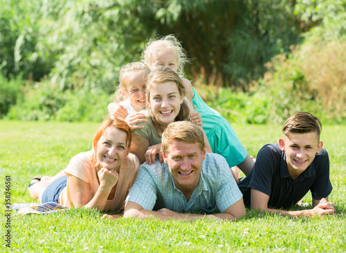 Glad man and woman with kids lying in park