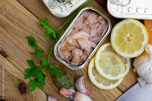 Tuna belly slices in oil in tin can with greens and lemon