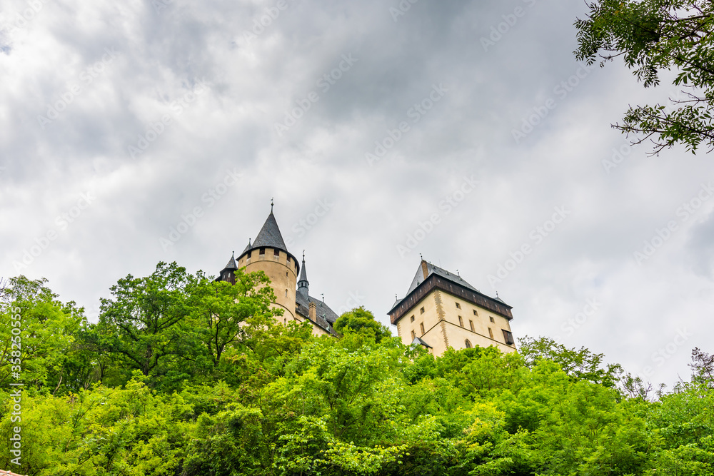 Famous medieval gothic castle Karlstejn on top of the hill. Beautiful stronghold is built by king Charles IV. Historical national heritage of Czech Republic is placed near Prague city. Cloudy weather Famous medieval gothic castle Karlstejn on top of the hill. Beautiful stronghold is built by king Charles IV. Historical national heritage of Czech Republic is placed near Prague city. Cloudy weather