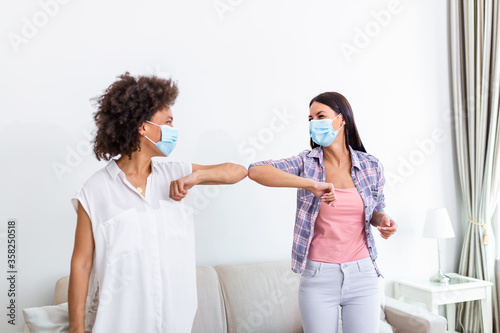 Elbow bump. New novel greeting to avoid the spread of coronavirus. Two women friends meet with bare hands. Instead of greeting with a hug or handshake, they bump elbows instead.