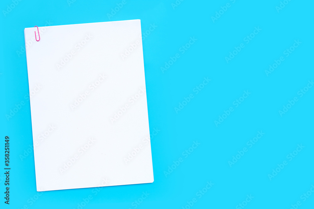 White paper with paperclip on blue background.
