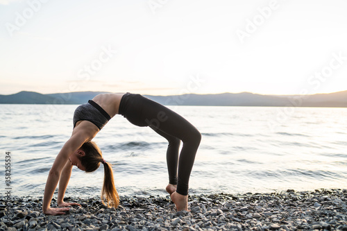 Young woman doing Yoga exercise in beautiful mountain lakes background