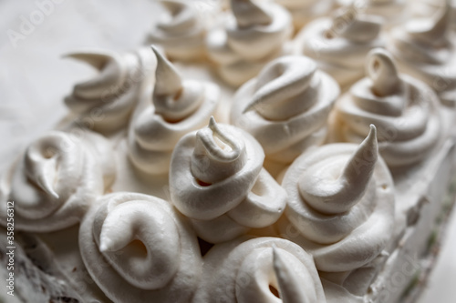 Cream dessert of airy Italian meringue. Whipped egg whites with hot sugar syrup. Light delicate cake cream in the form of a twisted peak on the top of the head in a spiral