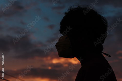 Silhouette of a kid wearing medical mask to prevent himself from the coronavirus disease