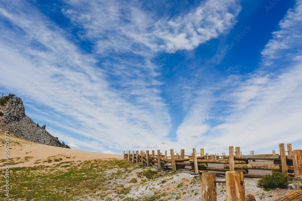 Wooden fence on the viewpoint around Crater Lake in summer with blue sky and cloudy.