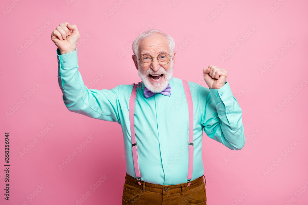 Photo of crazy funky grandpa raise fists celebrating pensioner party beginning ecstatic mood wear specs mint shirt suspenders violet bow tie pants isolated pink pastel color background