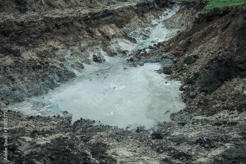 Dug hole in the ground is filled with water to the level. Swamp from the element that destroyed human activity. Stock abstract background