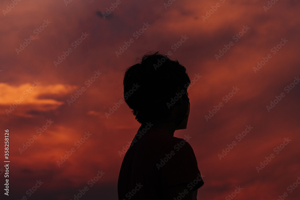 Silhouette of a kid in front of the beautiful dramatic sky during sunset Silhouette of a kid in front of the beautiful dramatic sky during sunset