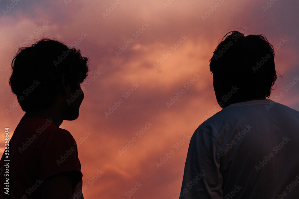 Silhouette of father and son staring at the sky
