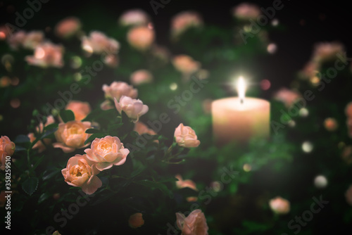 unscharfe brennende kerze inmitten von rosen, kondolenzkarte trauer konzept photo