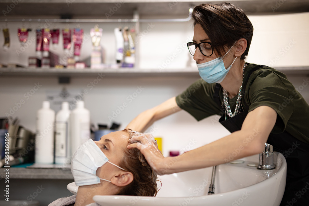Hairdresser and customer in a salon with medical masks during virus