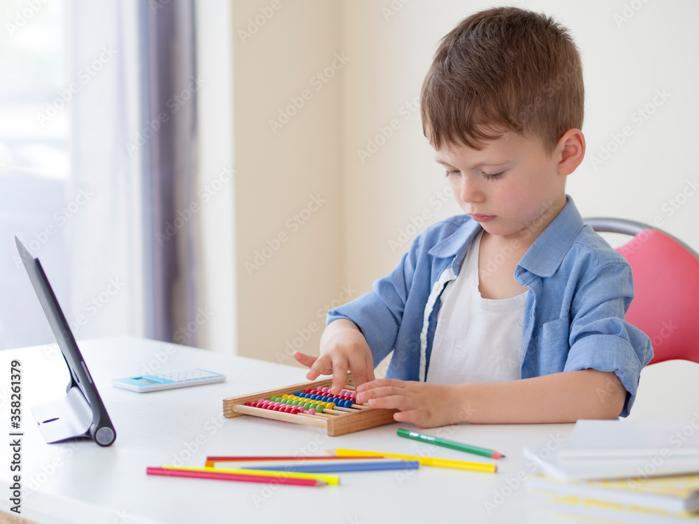 Online learning for children. Focused kid with tablet and Counting Number Frame Maths learns to count at home. Online math lesson Online learning for children. Focused kid with tablet and Counting Number Frame Maths learns to count at home. Online math lesson