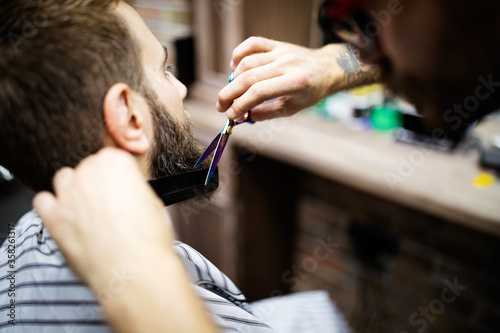 Barber shaving a bearded man in a barber shop  close-up