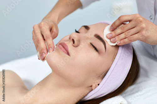 beautician cleanses female skin with a sponge. Perfect cleaning, woman is relaxing. spa treatment skincare face.