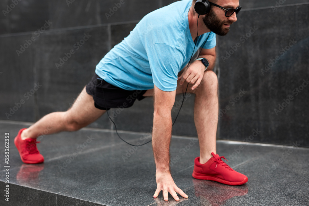 Modern sporty man making pause and stretching after jogging / exercise in urban environment. Modern sporty man making pause and stretching after jogging / exercise in urban environment.