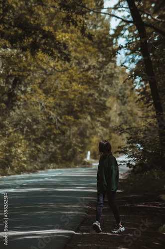 The girl walks alone near a forest 