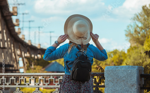 Girl in a hat and with a backpack on a background of a railway bridge. © Настя Монастырская