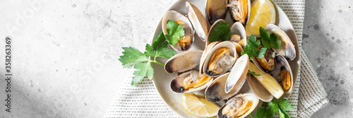 Cooked clams in a ceramic plate on a light gray table. Seafood dish. Banner	 photo