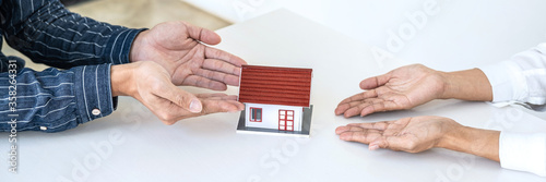 Estate agent holding house model to customer after signing rental lease