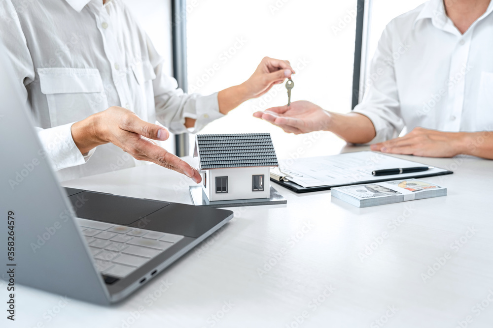 Estate agent holding filing keys to customer after signing rental lease Estate agent holding filing keys to customer after signing rental lease