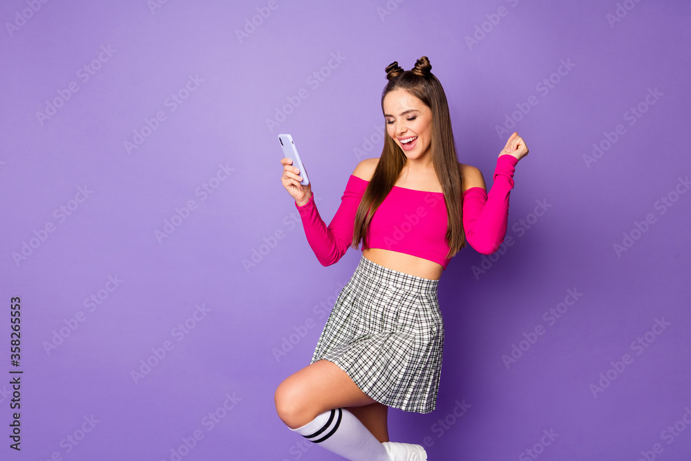 Naklejka premium Photo of pretty youngster crazy lady two funny buns hold telephone celebrate money income wear pink off-shoulders cropped top plaid short skirt isolated purple color background
