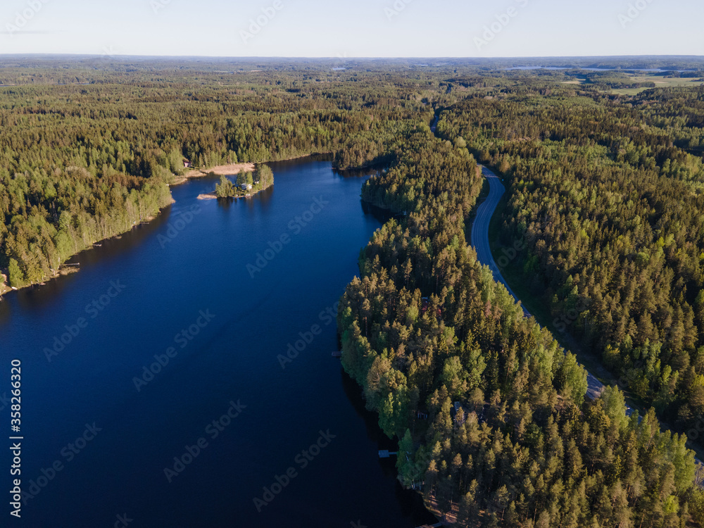 Aerial view of blue lakes with sun light in colorful summer time forest in Finland