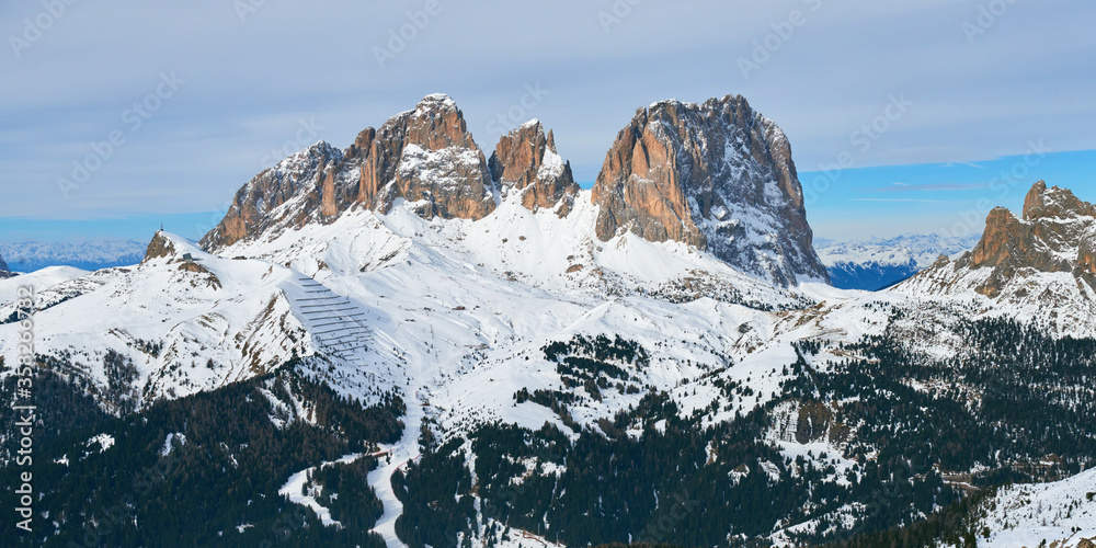 Winter panoramic view of rocky mountains and ski pistes in the Dolomites range in Italy.