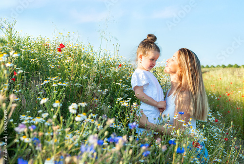 Mom and her pretty little daughter in a summer meadow