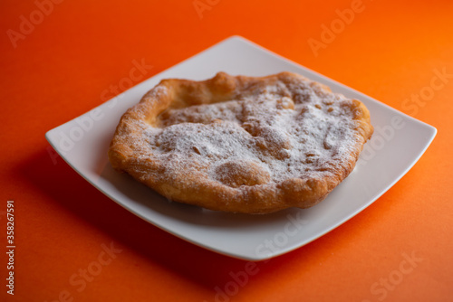 Traditional Transylvanian hungarian pastry, deep fried dough langos with sugar close up on white plate