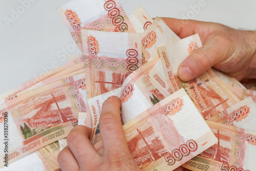 Men's hands hold a large amount of money with Russian banknotes of five thousand rubles