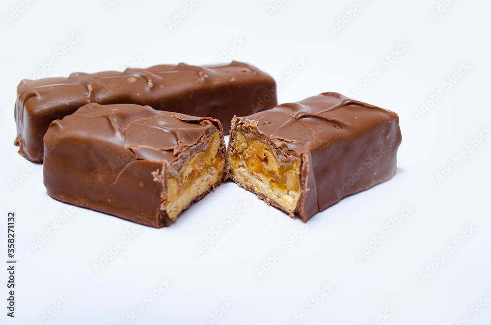 Two small snickers bars weighing 50 grams without packaging in macro are lying next to each other. Snickers one whole bar and another cut in half in macro. Chocolate cut in half close-up Two small snickers bars weighing 50 grams without packaging in macro are lying next to each other. Snickers one whole bar and another cut in half in macro. Chocolate cut in half close-up