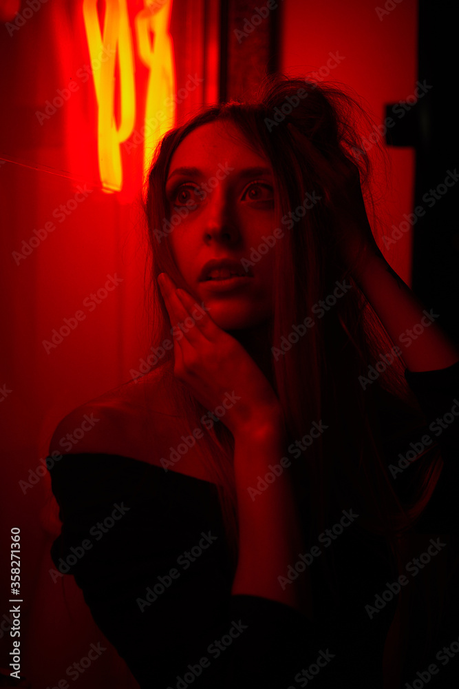 Red lighted girl near the shop window.