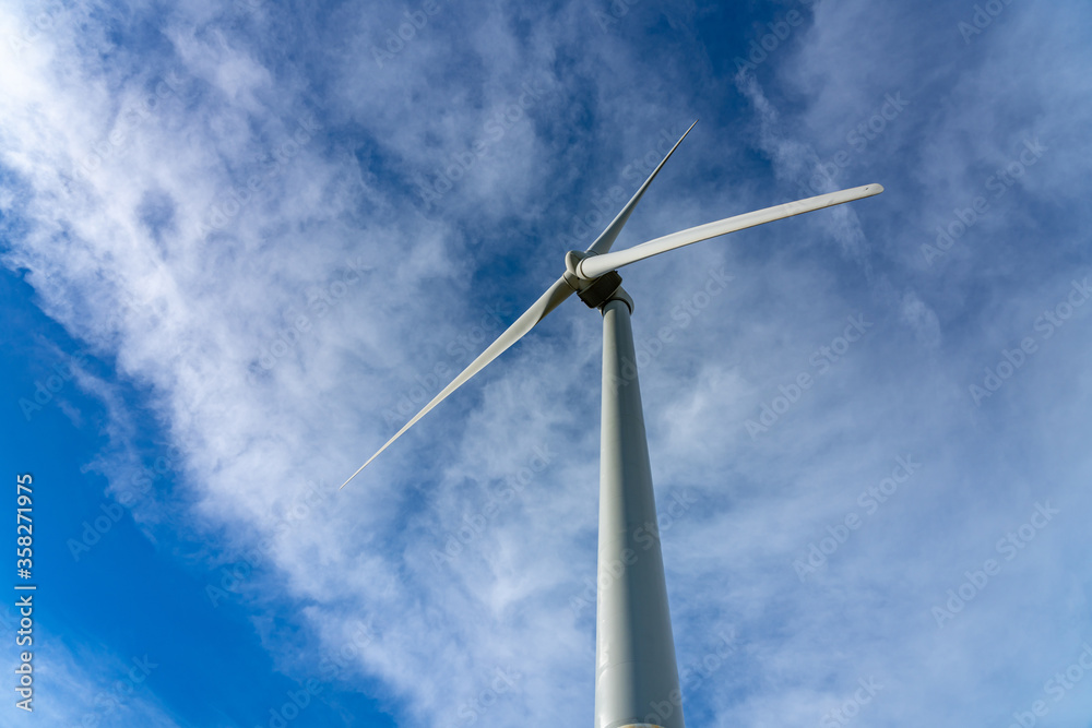 Close-up wind turbines or wind energy converter in sunny day with blue sky and white clouds
