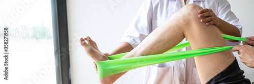 Doctor or Physiotherapist working examining treating injured leg of athlete male patient