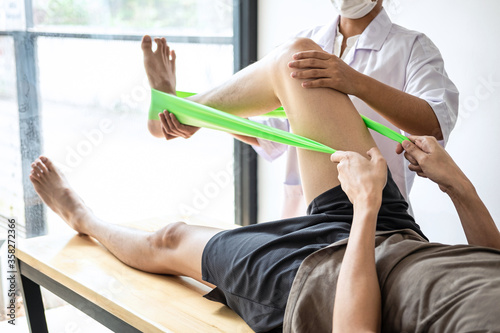 Doctor or Physiotherapist working examining treating injured leg of athlete male patient