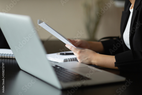 Caucasian woman holds a document in her hands. Close-up plan. Workplace in the office.