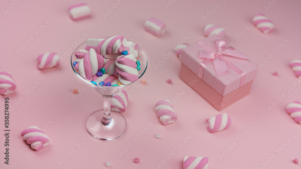 Lots of pink marshmallows on a pink background. Mashmallows in a transparant glass. Valentine's day. High quality photo.