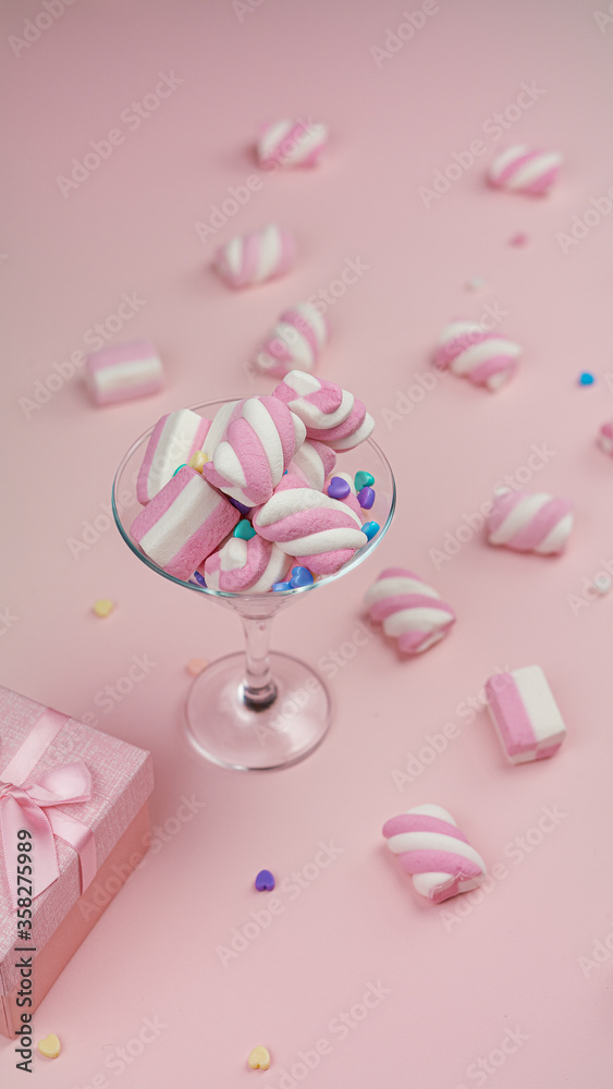 Lots of pink marshmallows on a pink background. Mashmallows in a transparant glass. Valentine's day. High quality photo.